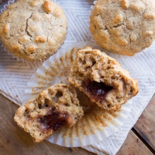 whole wheat peanut butter muffins with jelly centers torn in half on a paper towel