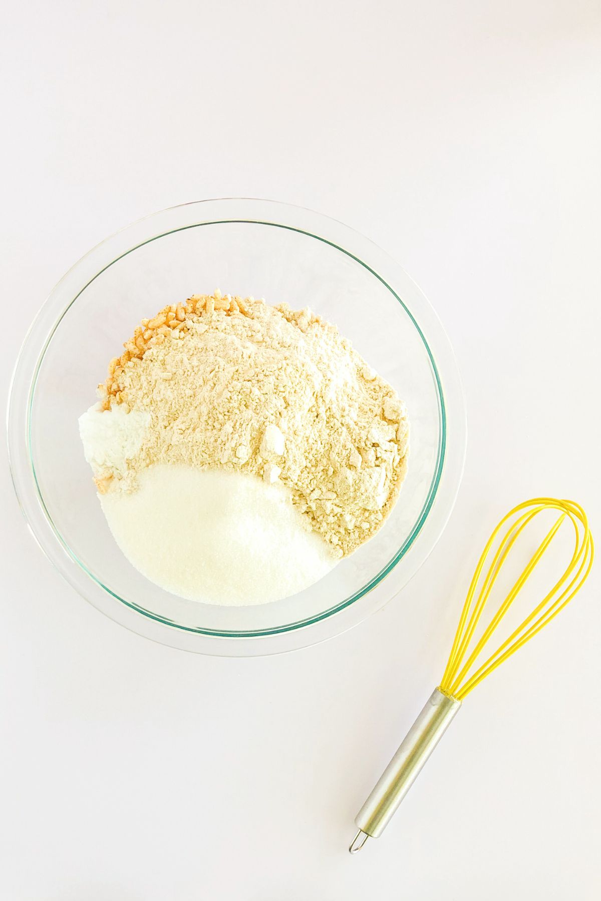 whole wheat pastry flour and puffed rice cereal in a glass bowl with a yellow spatula