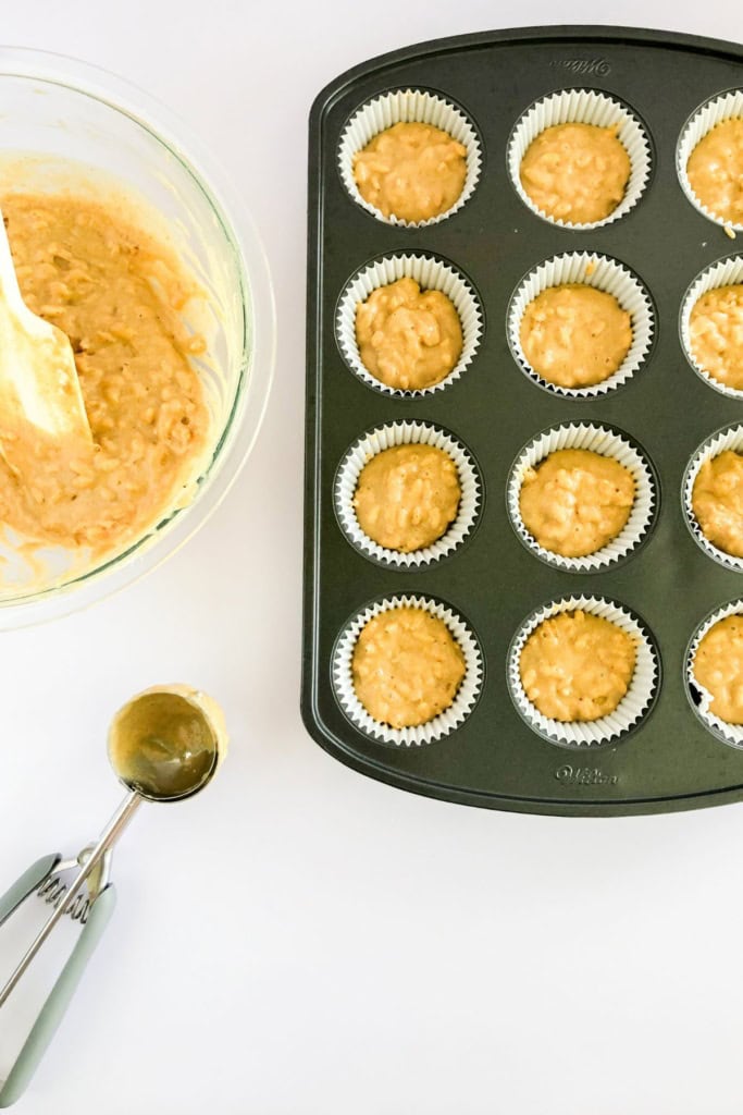a muffin tin with batter and a cookie scoop