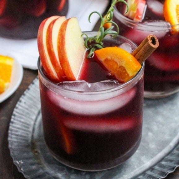 fall sangria with apple cider, red wine, and bourbon in a short glass topped with apple and orange slices