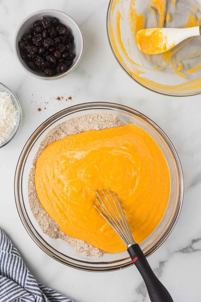 sweet potato muffin batter in a glass bowl with a metal whisk