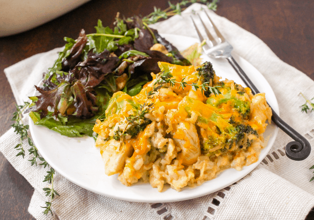 Chicken broccoli casserole on a white plate next to a green side salad.