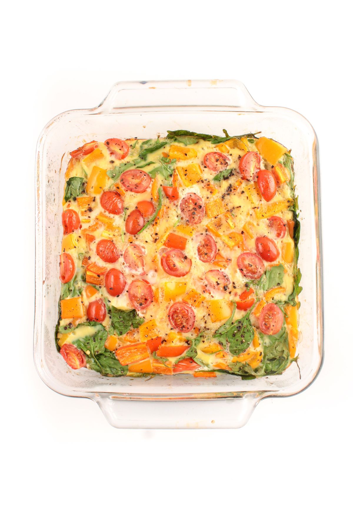 baked eggs with vegetables in a glass baking dish