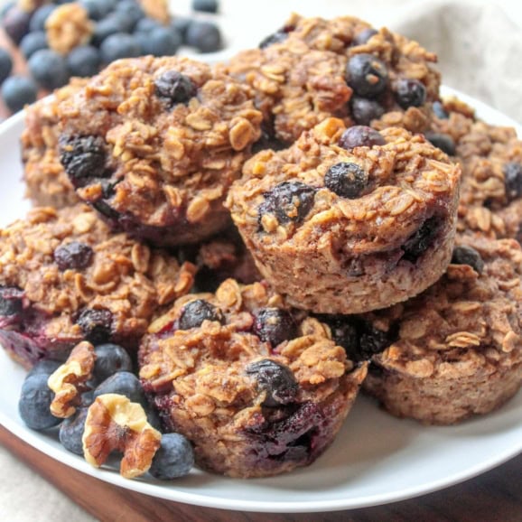 a pile of banana blueberry oatmeal muffins on a white plate