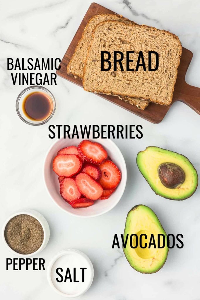 strawberries, avocados, bread, and balsamic vinegar on a white marble surface