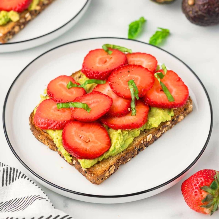 strawberry toast with avocado and balsamic glaze on a white plate