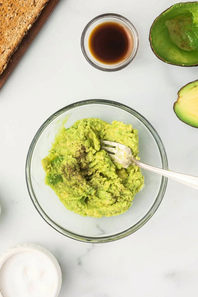 mashed avocado in a glass bowl with a fork