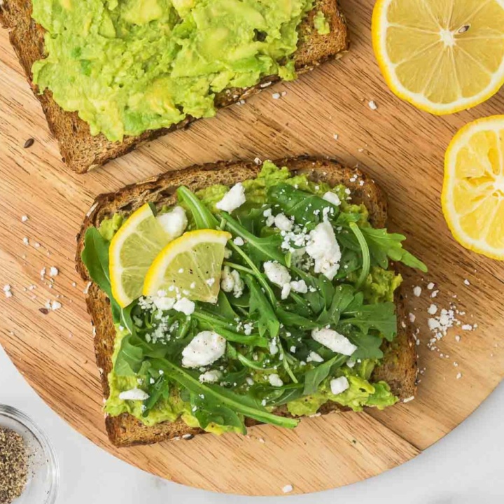 avocado toast with goat cheese and arugula on a wooden platter