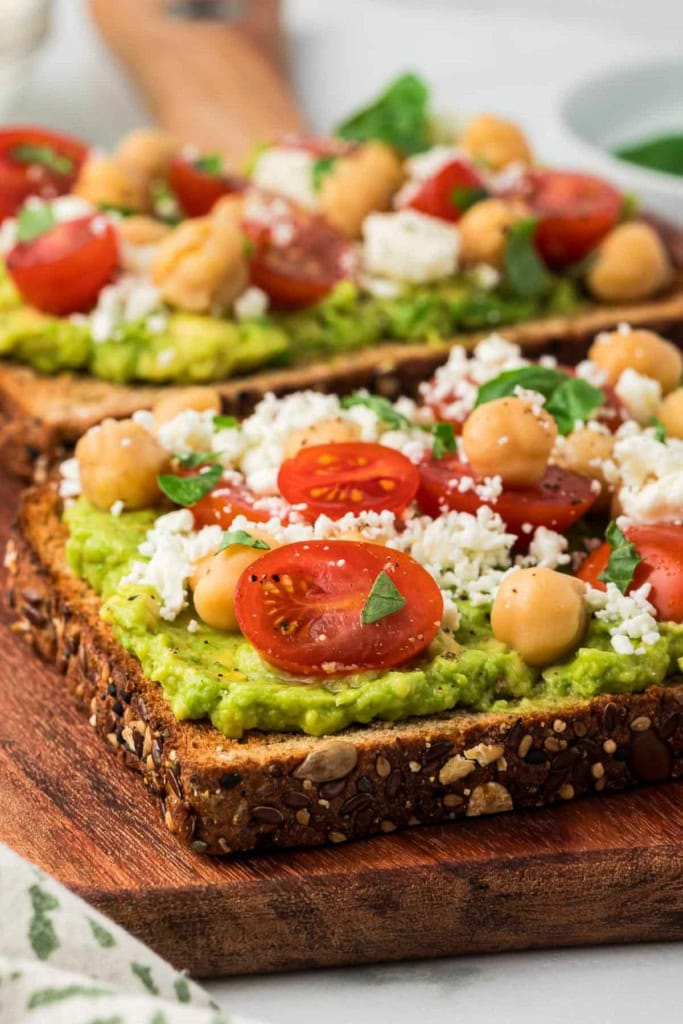 feta avocado toast with chickpeas on a wooden board