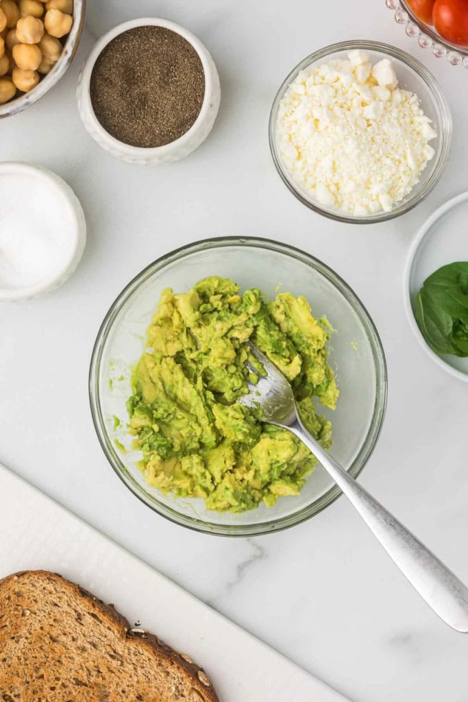 a glass bowl with mashed avocado 