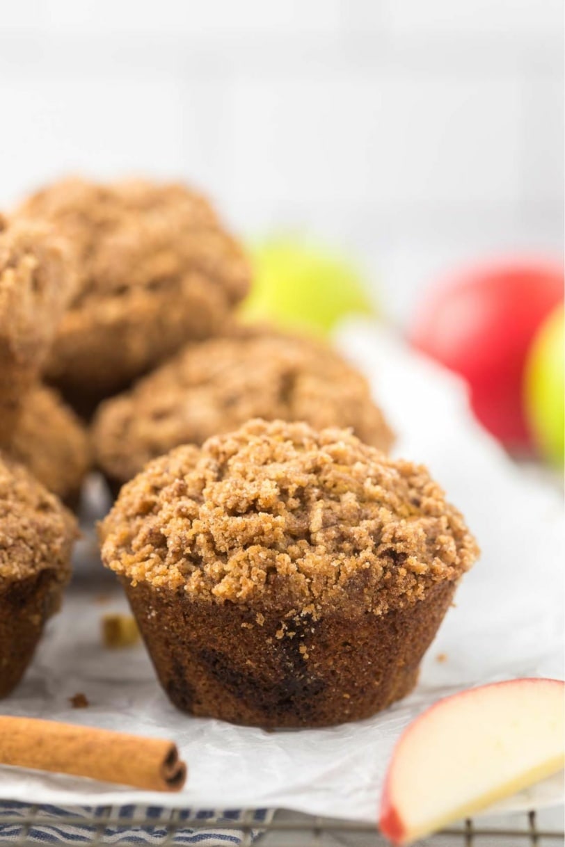 an apple muffins with cinnamon crumble topping next to a cinnamon stick