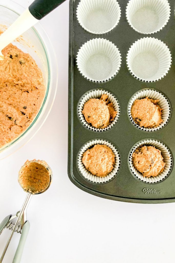 carrot cake batter in a muffin tin with a metal scoop