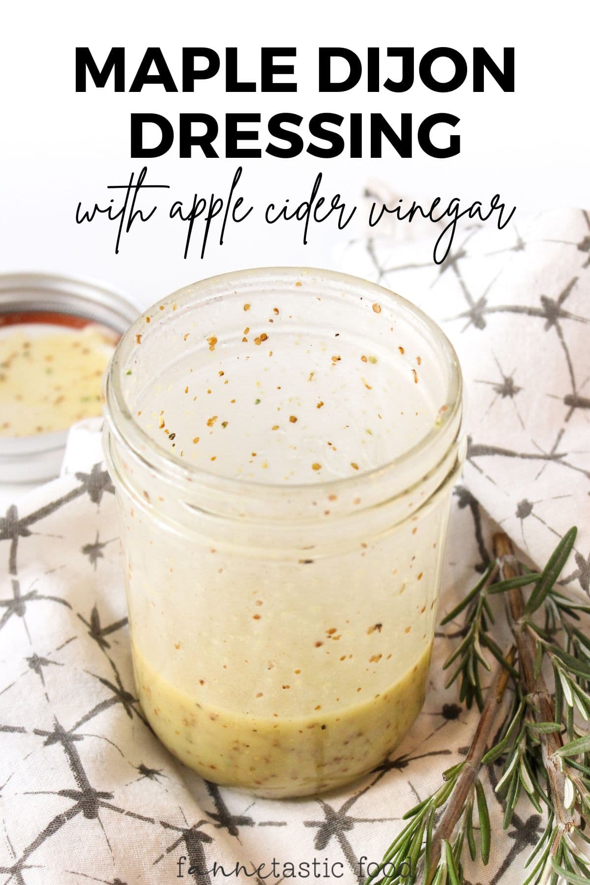 maple dijon dressing with apple cider vinegar in a mason jar with a sprig of rosemary beside it