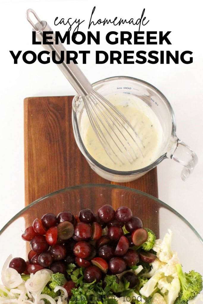 lemon Greek yogurt dressing being poured from a glass measuring cup over a salad