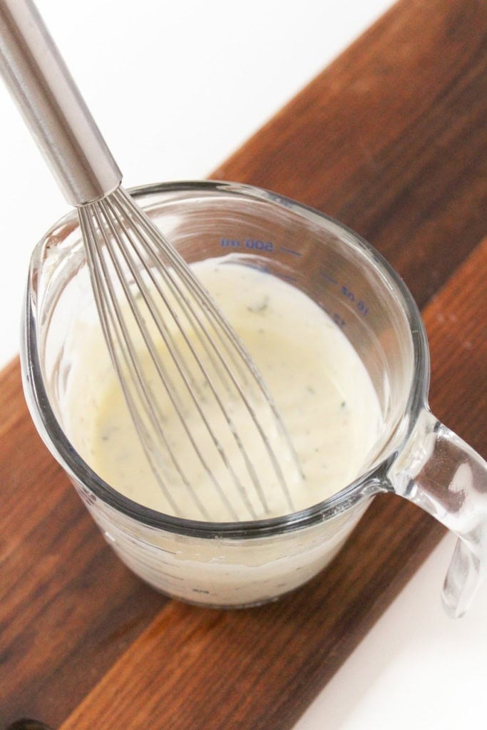 lemon Greek yogurt dressing in a glass measuring cup with a metal whisk