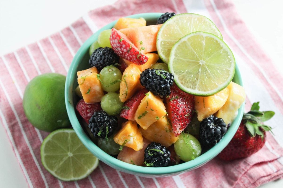 fruit salad with yogurt dressing and limes in a bowl