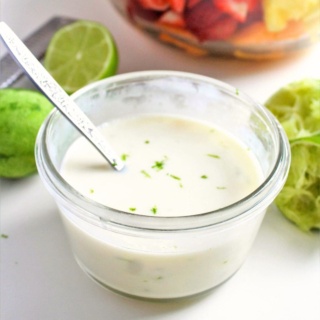 Greek yogurt dressing in a small glass bowl with limes