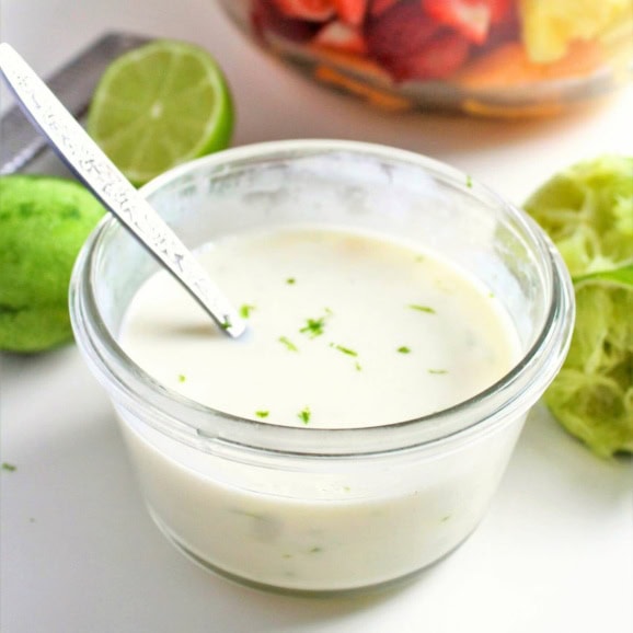 Greek yogurt dressing in a small glass bowl with limes