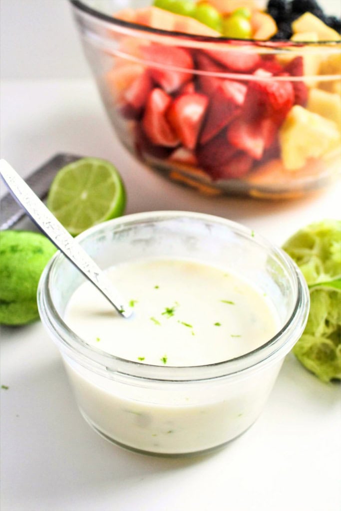 Greek yogurt lime dressing in a small glass bowl next to a bowl of fruit