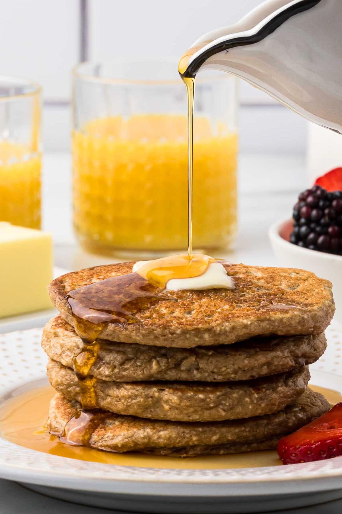 stack of cottage cheese protein pancakes on a plate with maple syrup being poured on top