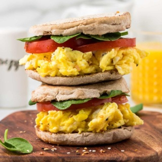 cottage cheese scrambled egg sandwiches with english muffins stacked on top of each other on a wooden board