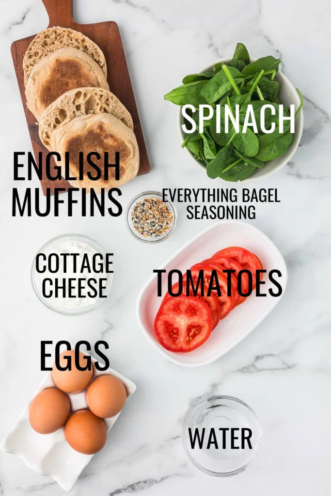 cottage cheese, eggs, tomatoes, spinach, and English muffins on a white marble background