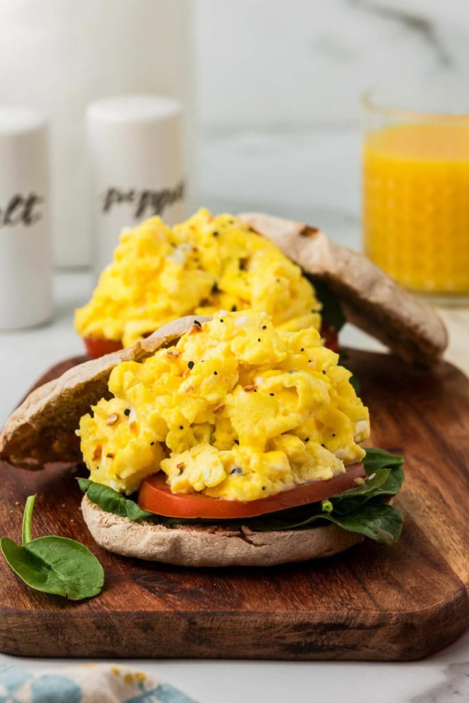 cottage cheese scrambled eggs on English muffins sitting on a wooden platter