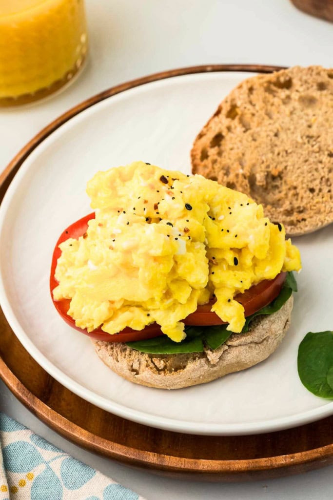 scrambled eggs and cottage cheese on a whole wheat English muffin on a plate