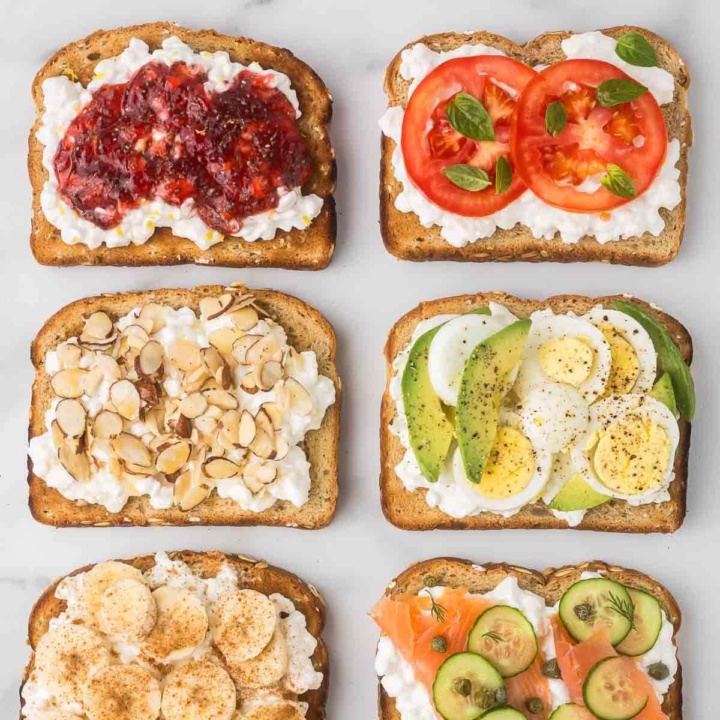 six slices of cottage cheese toast with sweet and savory toppings on a white marble countertop