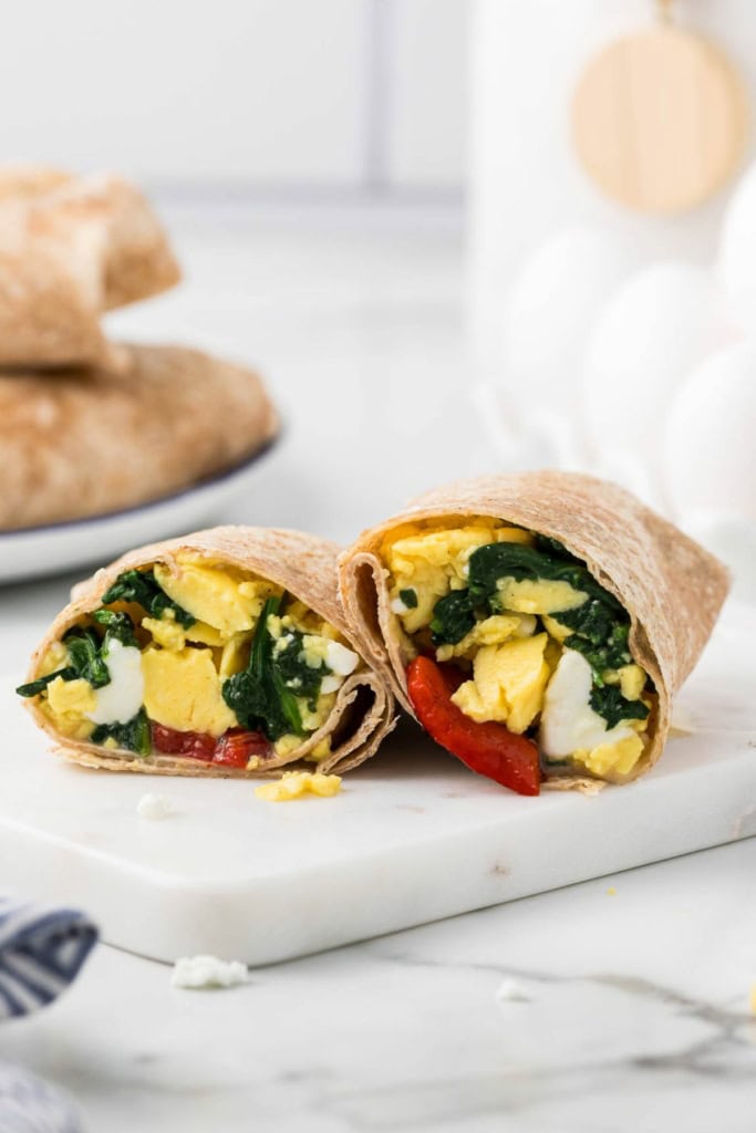 spinach feta wrap with eggs sliced in half on a marble platter