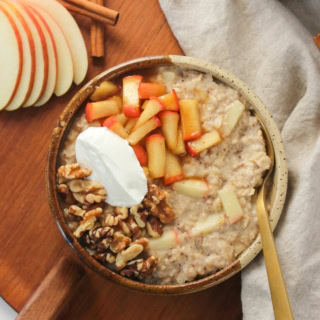 a bowl of oatmeal with sauteed apples, pecans, and Greek yogurt on top