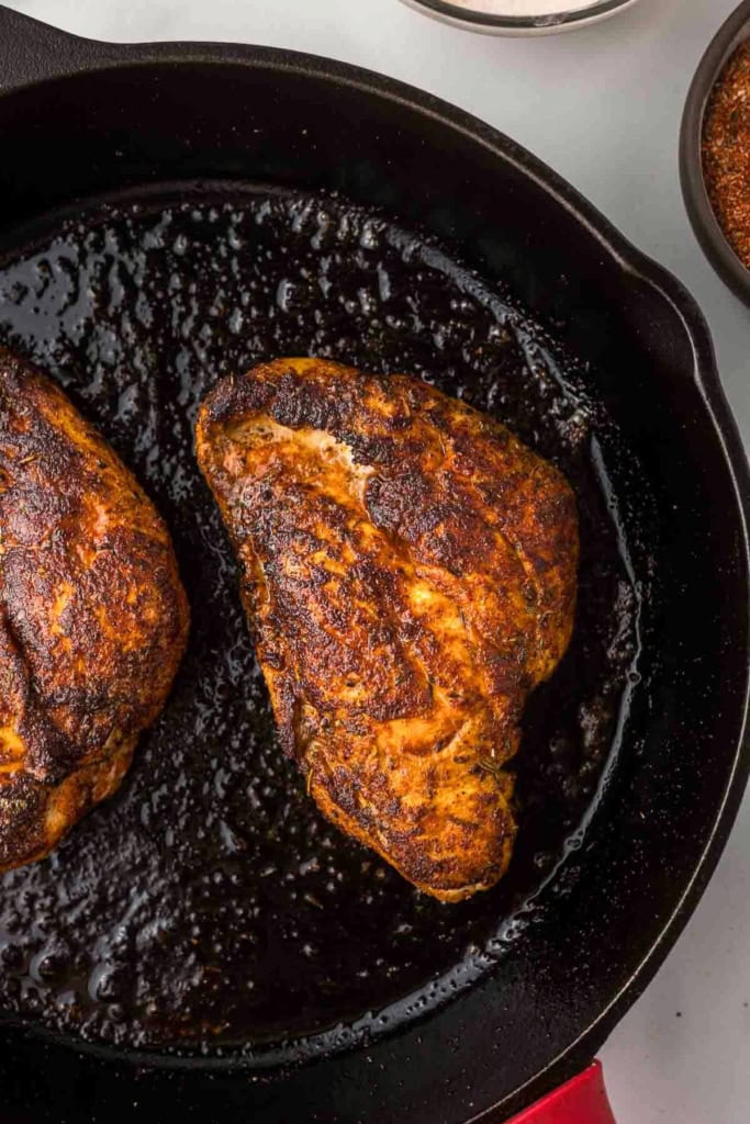 chicken breasts seared on a black cast-iron skillet