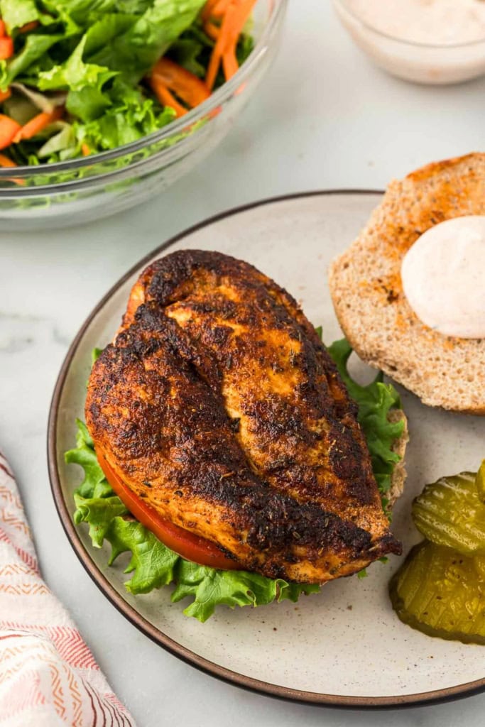 blackened chicken breast on a bun with lettuce and tomato