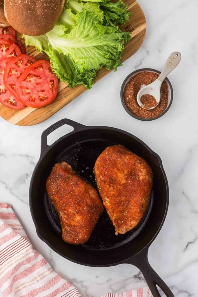 blackening seasoning rubbed on chicken breasts in a cast-iron skillet