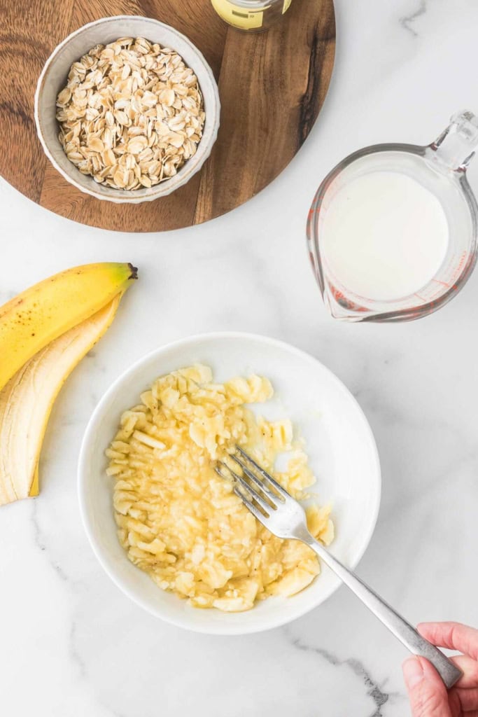 mashed banana in a white bowl with a fork